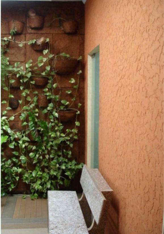 Casa moderna com fachada pintada em tons terrosos, utilizando tintas ecológicas à base de insumos naturais e não tóxicos, cercada por jardim com cactos e plantas resistentes.