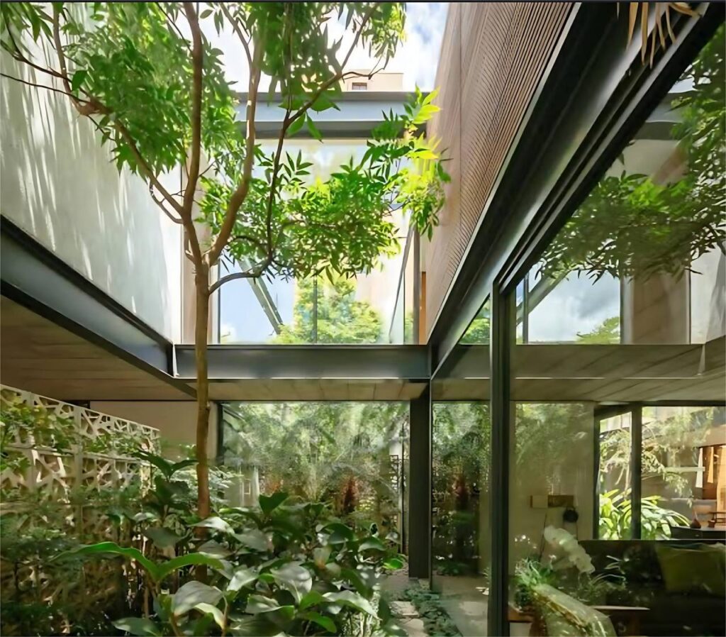 Decoração Biofílica em residência moderna com árvores internas e vidro.