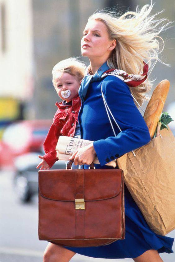 Mãe empreendedora correndo com o filho no colo e uma bolsa de trabalho, representando o desafio do planejamento do tempo no dia a dia.