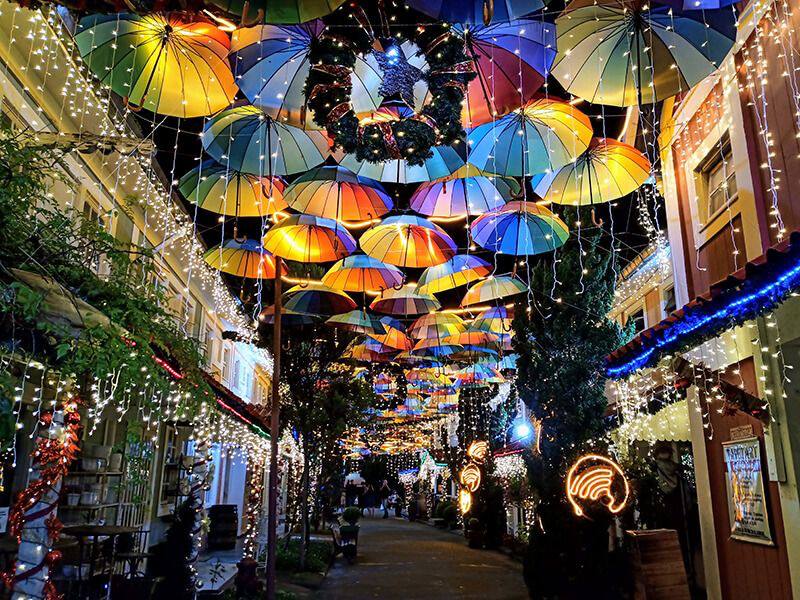 Decoração natalina colorida com guarda-chuvas iluminados na Vila de Penedo, uma das cidades natalinas no Brasil mais famosas para visitar com crianças.