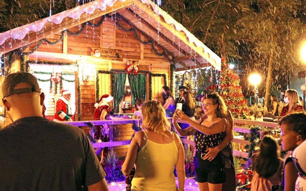 Visitantes em frente à Casa do Papai Noel decorada para o Natal em Holambra, uma das cidades natalinas mais charmosas do Brasil.”